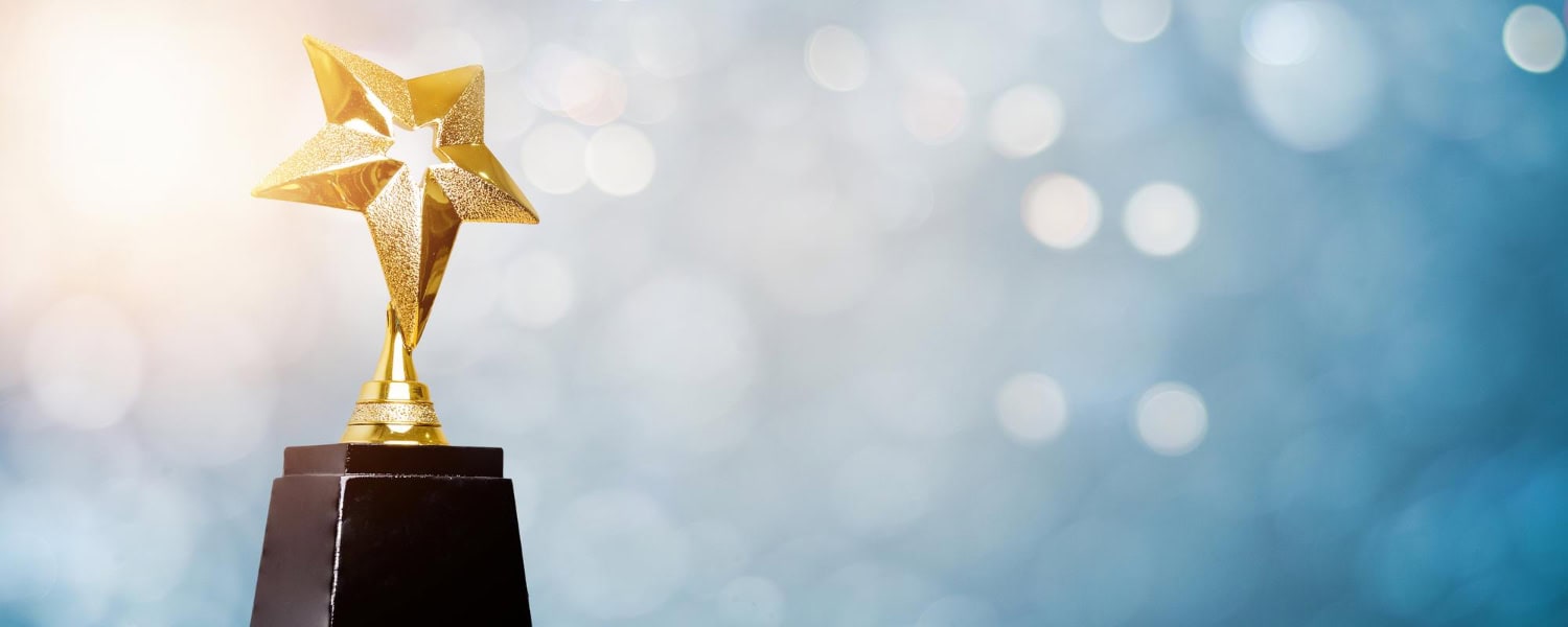 Golden star trophy on a black base with a blurred background.