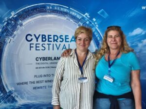 Two women at CyberSea Festival 2026, smiling, with festival backdrop.